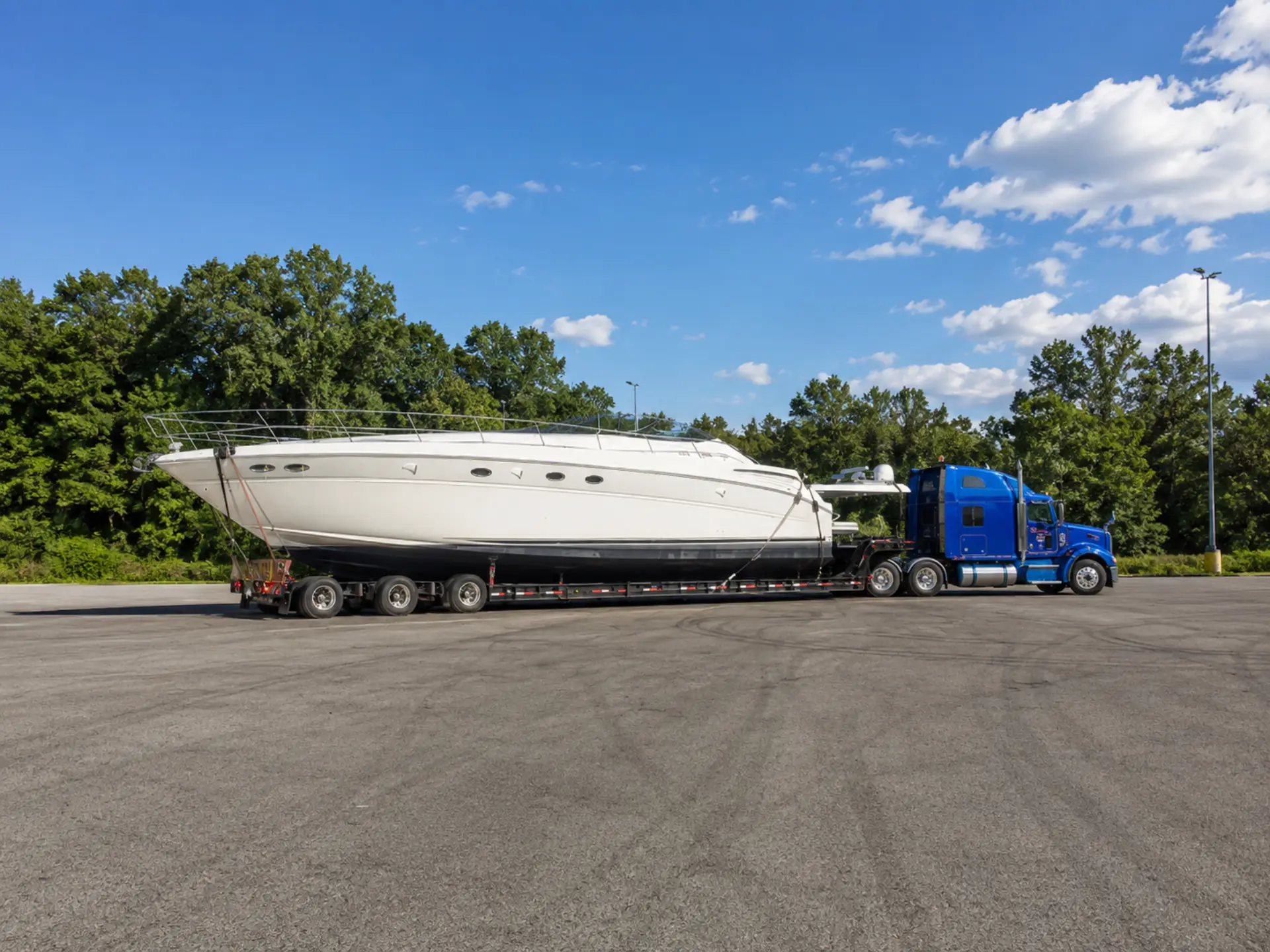 White sport cruiser on a trailer behind a semi-truck in a parking lot